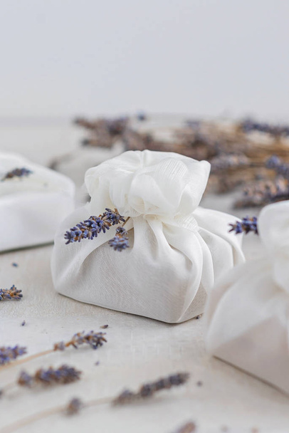 Beyaz furoshiki kumaşıyla sarılmış ve lavanta çiçekleriyle süslenmiş bir hediye. Çevre dostu hediye.. - Fotoğraf, Görsel