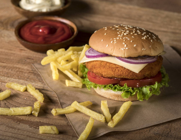 Frischer Burger mit Pommes und Soßen auf Holzboden - Foto, Bild