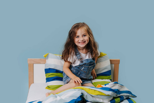 Happy smiling girl plays in her bed. - Zdjęcie, obraz
