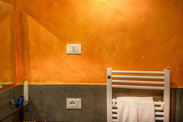 Towel warmer and electric socket on an orange wall  - Φωτογραφία, εικόνα