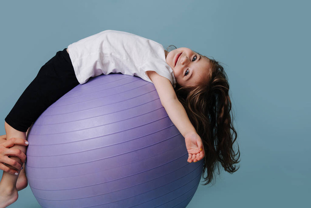 girl lies back on lilac fitness ball. - Фото, зображення