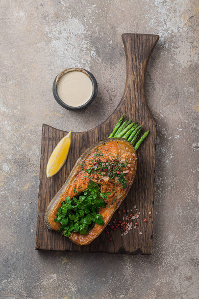 Fried salmon steak with vegetables on wooden board, copy space - Фото, изображение