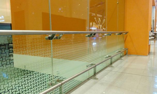 Vidrio templado Tabique de vidrio de altura completa junto con protección de pasamanos de acero inoxidable con paredes de fondo de color naranja
 - Foto, Imagen