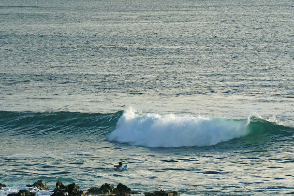 Homme nageant sur planche de surf pour attraper des vagues sur l'océan Pacifique, Hanga Roa, Île de Pâques, Chili
 - Photo, image