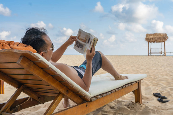 Young man reading book on the beautiful beach - Photo, Image