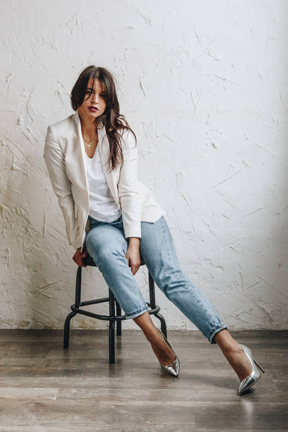 Beautiful young woman wearing white blazer and blue jeans - Foto, afbeelding