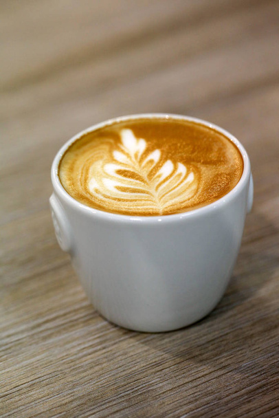 Il caffè barista versò il latte nel caffè e creò una bella foglia
. - Foto, immagini