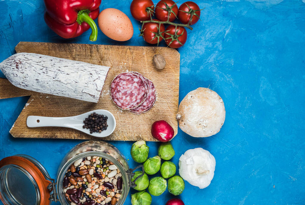 Konyha - friss színes organikus zöldségek rögzített felülről (felülnézet, lapos nyugágy). Kék háttér. Elrendezés szabad szöveges (másolt) hellyel. Vegán kaja. egészséges élelmiszerek - Fotó, kép