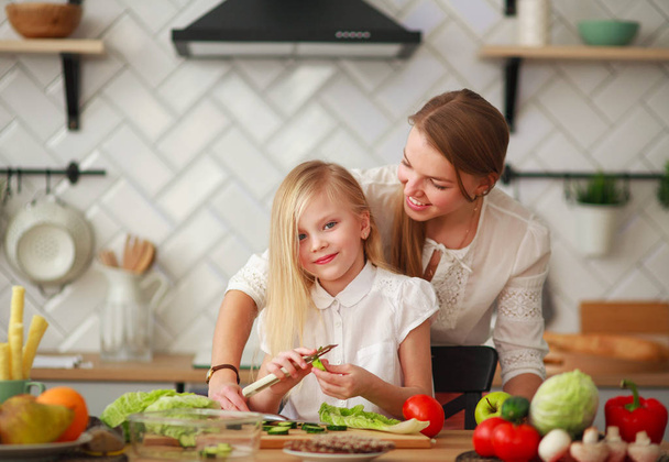 Mother teaches her child daughter how to cook in kitchen - Photo, Image