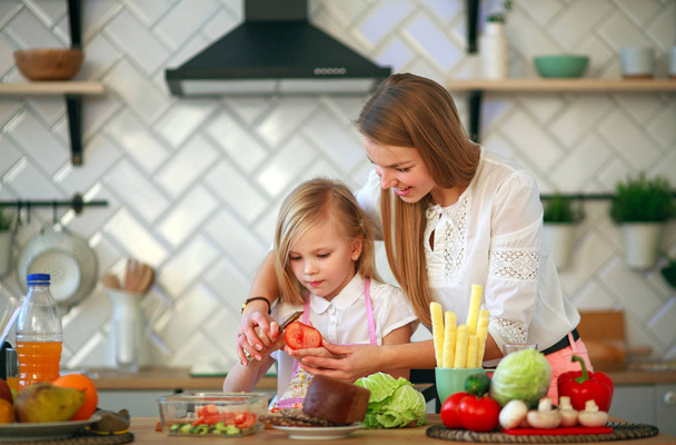 Mère enseigne à sa fille enfant comment cuisiner dans la cuisine
 - Photo, image