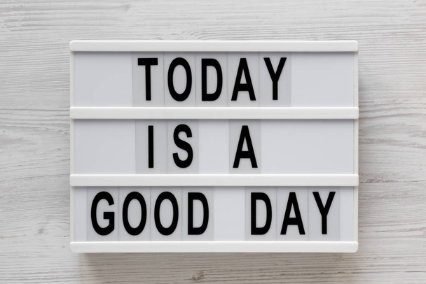 "Σήμερα είναι μια καλή μέρα" λέξεις σε ένα lightbox σε ένα λευκό ξύλινο πίσω μέρος - Φωτογραφία, εικόνα