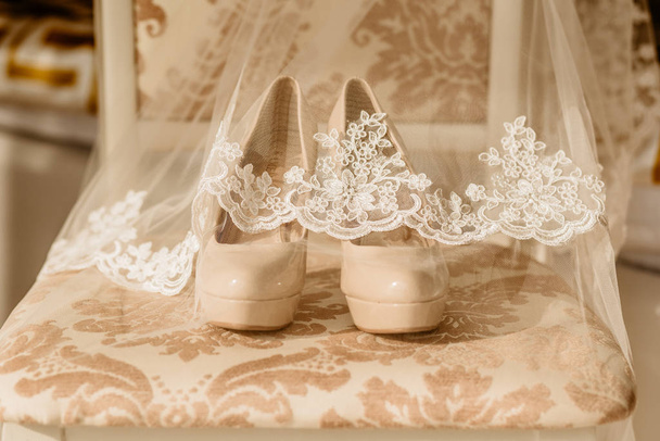 Bruids hoge hak schoenen voor gelukkige bruiloft onder sluier op de stoel - Foto, afbeelding