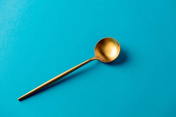 χρυσό κουτάλι σε μπλε φόντο απομονωμένο  - Φωτογραφία, εικόνα