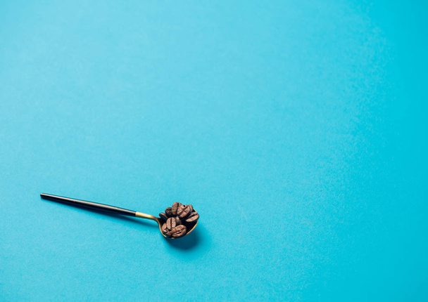 teaspoon with coffee grains on a blue background - Foto, Imagen
