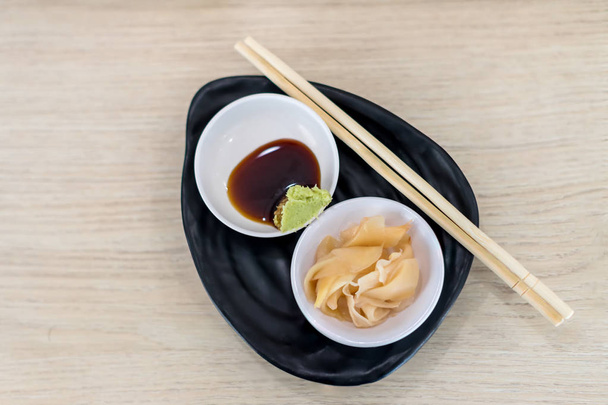 Ginger and wasabi on plate. traditional Japanese condiments - wasabi, ginger and soy sauce - a set for sushi on table. Pickled ginger with soy sauce and wasabi for sushi. - Fotografie, Obrázek