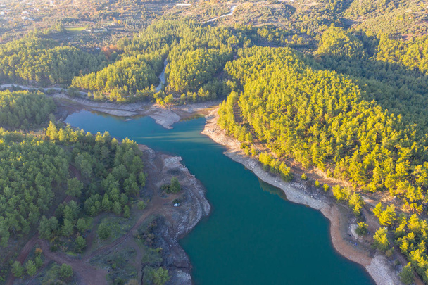 Природное экологическое озеро в окружении сосен между горами
 - Фото, изображение