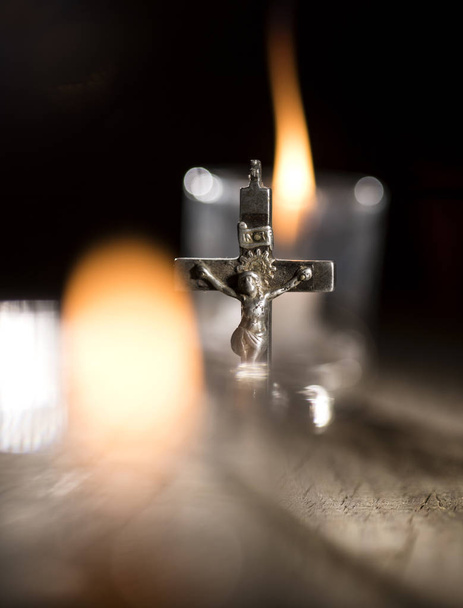 Metal cross and candles on dark background - 写真・画像