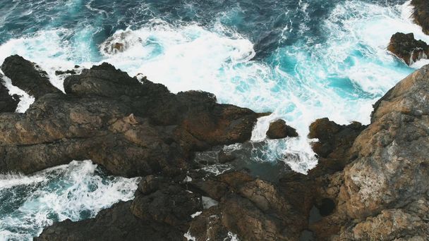 Aerial view of the ocean waves and the beautiful rocky coast of the island of Tenerife. Dangerous waves crash against large rocks - Fotografie, Obrázek