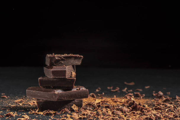 dark chocolate on a stone. Dark background. - Фото, изображение