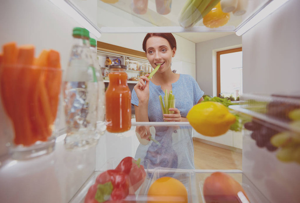 Νεαρή γυναίκα παίρνει φρέσκα και υγιή λαχανικά από το ψυγείο και την προετοιμασία γεύματος, διατροφή και τρόπο ζωής έννοια - Φωτογραφία, εικόνα