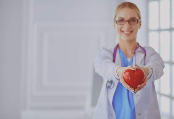 Female doctor with stethoscope holding heart in her arms. Healthcare and cardiology concept in medicine - Foto, Imagem