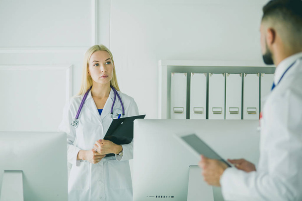 Woman doctor standing with folder at hospital - Фото, изображение