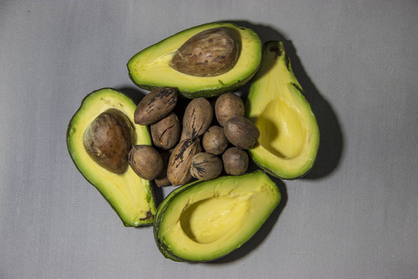 geschnittene Stücke von Avocado-Nüssen auf grauem Hintergrund - Foto, Bild