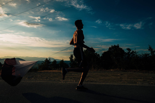 Sprinter. Man running on road at high speed in beautiful exotic mountain landscape against blue sky - Φωτογραφία, εικόνα