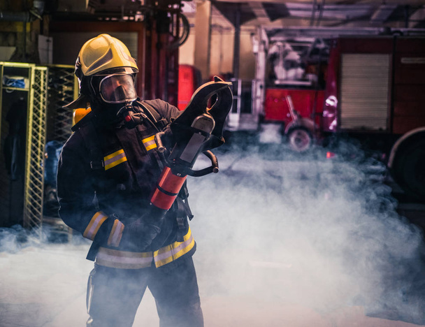 Портрет молодого пожежника, що стоїть і тримає бензопилу в
 - Фото, зображення