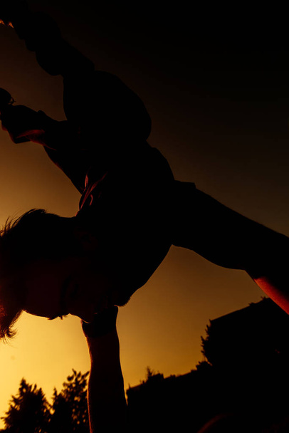 Parkour moves uitgevoerd door een acrobatische jongen in de lokale skate speeltuin - Foto, afbeelding