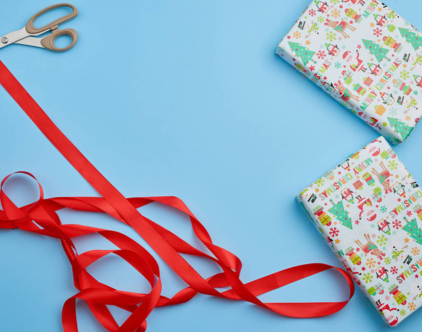Подарок, завернутый в разноцветную бумагу и красную ленту на синей набережной
 - Фото, изображение