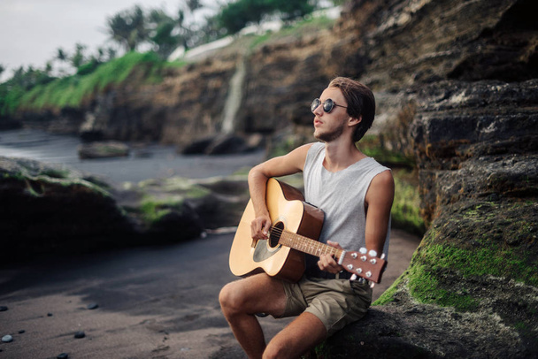 Романтичный молодой человек с гитарой на пляже - Фото, изображение