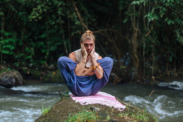 Yoga practice and meditation in nature. Man practicing near river - Фото, изображение