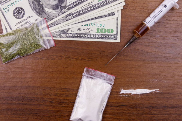 Különböző típusú drogok: kokain, heroin fecskendő, szárított kannabisz és dollár az asztalon. Kábítószer-használat, kábítószer-kereskedelem, bűnözés és függőség - Fotó, kép