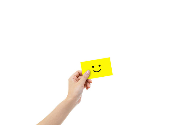 Asiakkaan palaute Concept: Käsi tilalla hymy kuvake symboli keltainen kortti eristetty valkoisella pohjalla
. - Valokuva, kuva