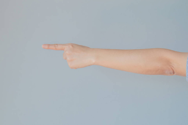Hand of female gesturing in single pointing finger shape with gray background. - Foto, afbeelding