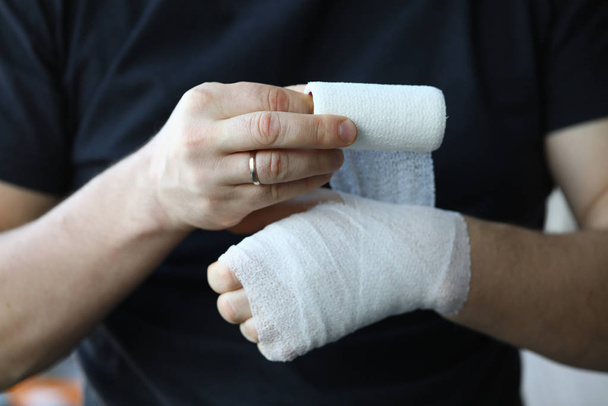 Ανδρικό χέρι με σφιχτό ελαστικό επίδεσμο στο χέρι closeup - Φωτογραφία, εικόνα