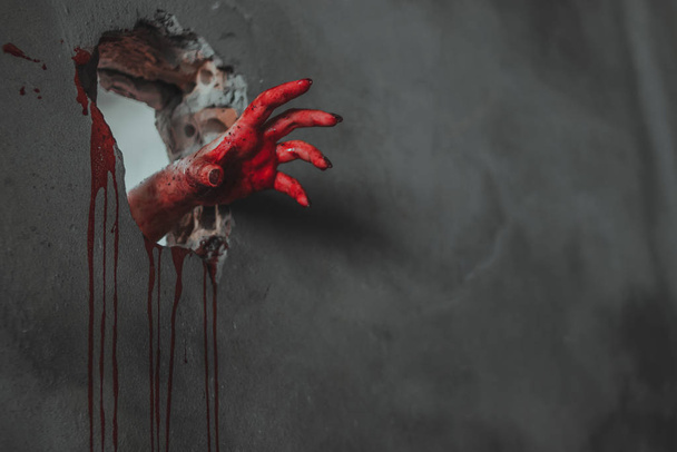 Zombie hand through cracked wall. Halloween horror concept. - Photo, Image