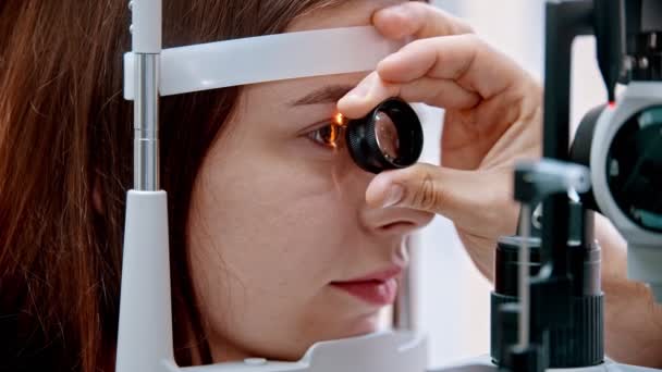 眼科医-眼科医は特殊な拡大鏡で女性の視力を見ています - 映像、動画