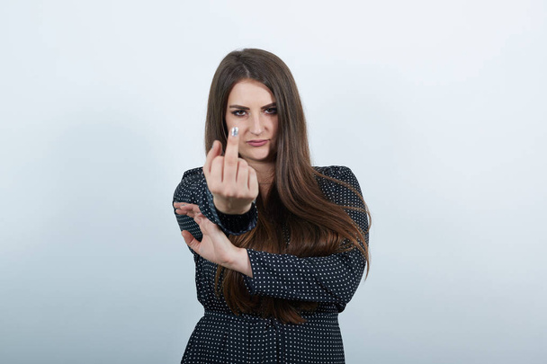 Mujer agresiva sobre pared gris aislada, mostrando el dedo medio en la cámara
 - Foto, Imagen