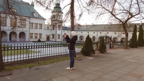 Girl tourist makes a photo of palace in the old square - Video