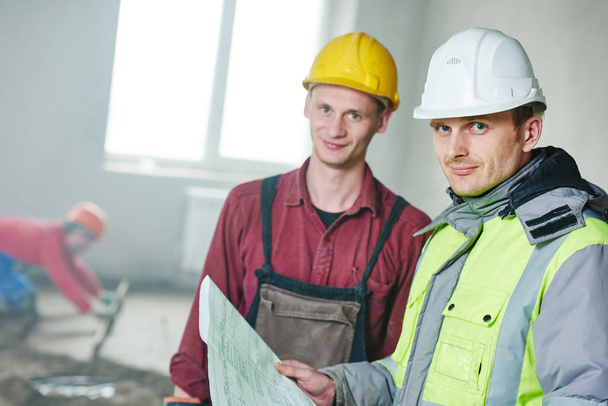 foreman builder and construction worker with blueprint in indoor apartment - Valokuva, kuva