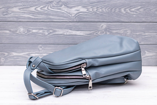 blauer Rucksack aus Kunstleder auf Holzgrund. Tasche aus Kunstleder. - Foto, Bild