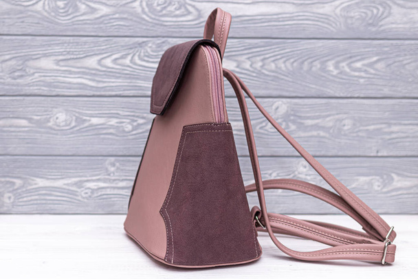 Синтетическая кожа розовый рюкзак на деревянном фоне. Кожаная сумка
. - Фото, изображение