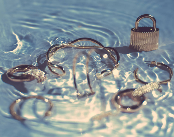 Bracelets dorés, boucles d'oreilles, bagues, bijoux sur fond bleu
 - Photo, image