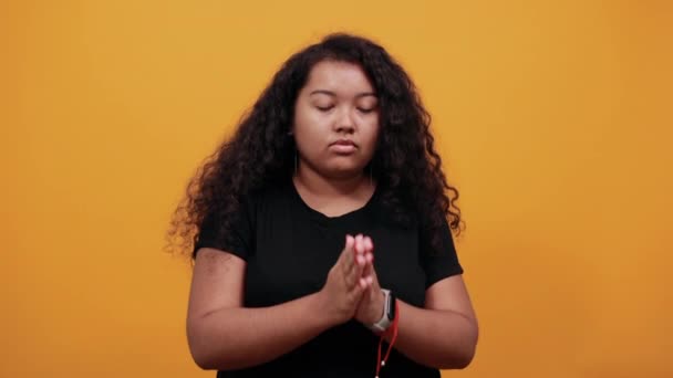 Poważna kobieta z nadwagą trzyma ręce razem, modli się, patrzy w górę - Materiał filmowy, wideo