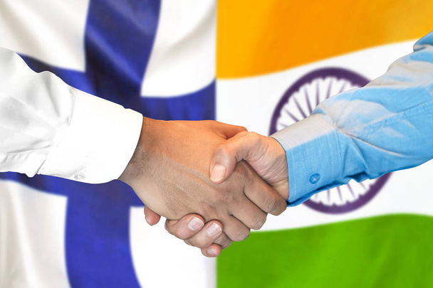 フィンランドとインドの旗の背景で握手. - 写真・画像