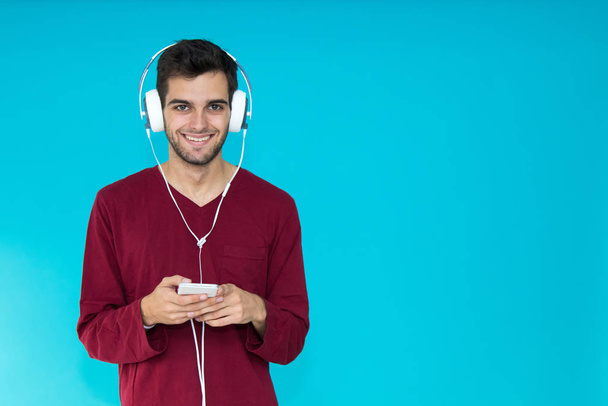 mladý muž s chytrým telefonem nebo mobilní telefon sluchátka izolované na barevném pozadí - Fotografie, Obrázek