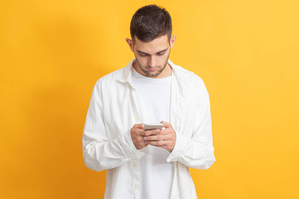 portrait of young man with mobile phone on color background - Foto, Imagen