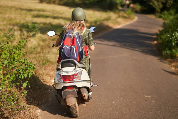 Une fille en robe verte conduit un scooter
.  - Photo, image
